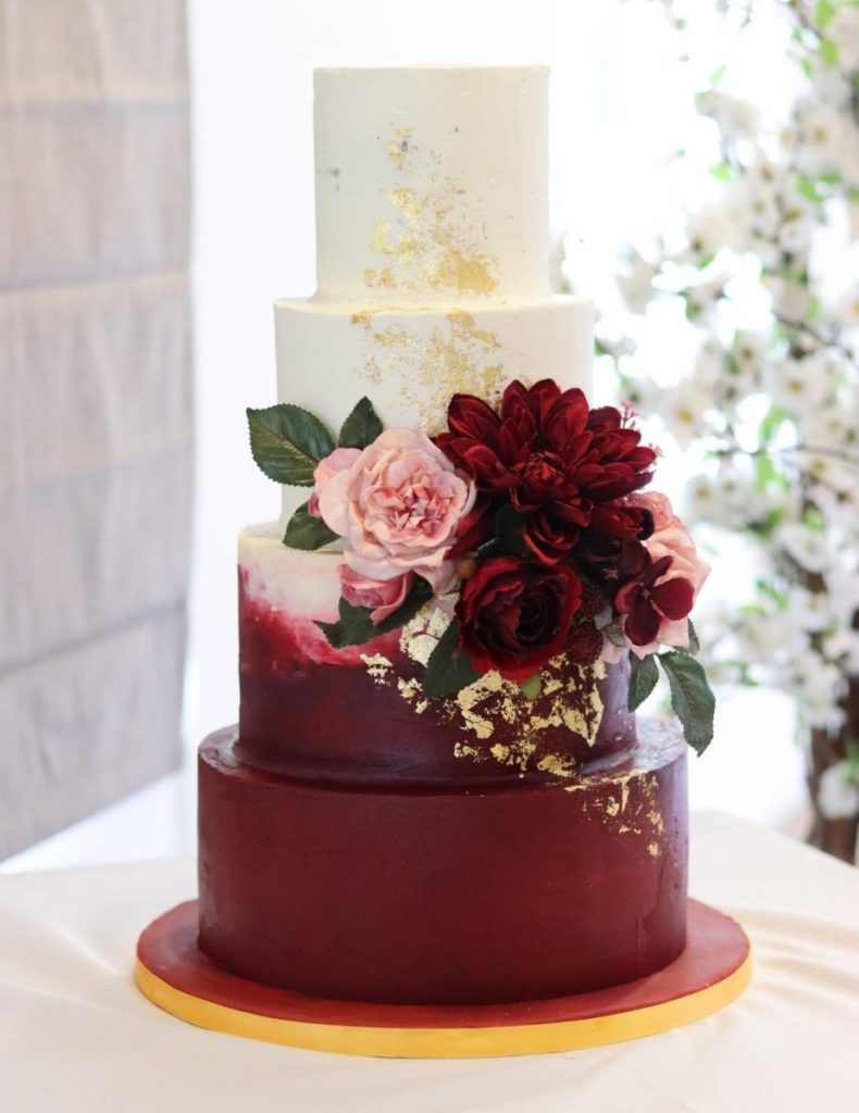 In questa foto una torta matrimonio a quattro piani posizionata decorata con fiori e pennellate nel colore Viva Magenta