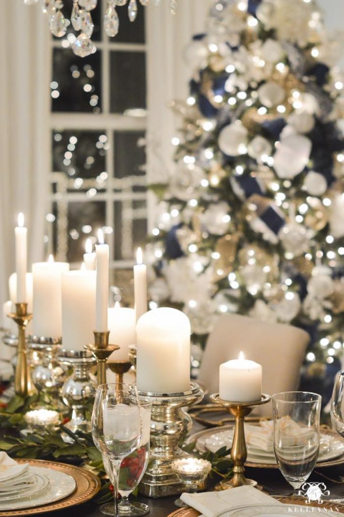 In questa foto un tavola per matrimonio a tema Natale decorata con portacandele di colore dorato e candele di grandi di dimensioni di colore bianco