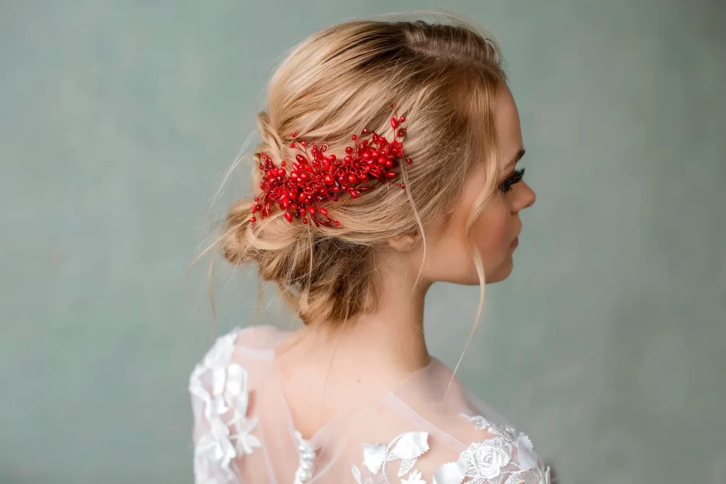 In questa foto una modella porta tra i capelli un accessorio da sposa composto da bacche e perline di colore rosso