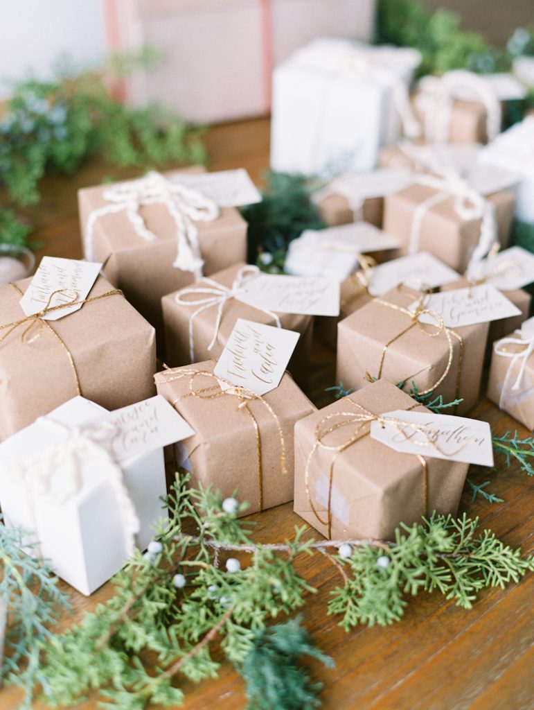 In questa foto escort card per matrimonio natalizio legate a piccoli pacchetti regalo di colore beige e bianco