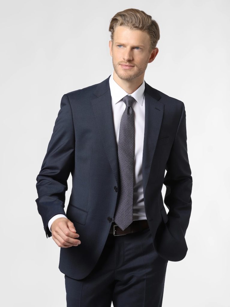 In questa foto un modello indossa un modello di abito da sposo classico di colore blu scuro abbinato ad una cravatta di colore grigio di Hugo Boss