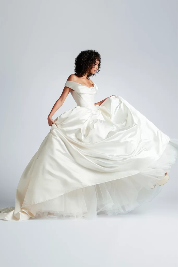 In questa foto una modella gira indossando un abito da sposa ampio in duchesse con scollo a barca di Vivienne Westwood