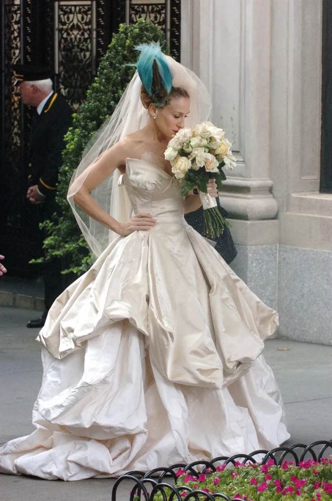 In questa foto Sarah Jessica Parker sul set di Sex and the City mentre annusa un bouquet da sposa e indossa il Cloud Dress disegnato da Vivienne Westwood