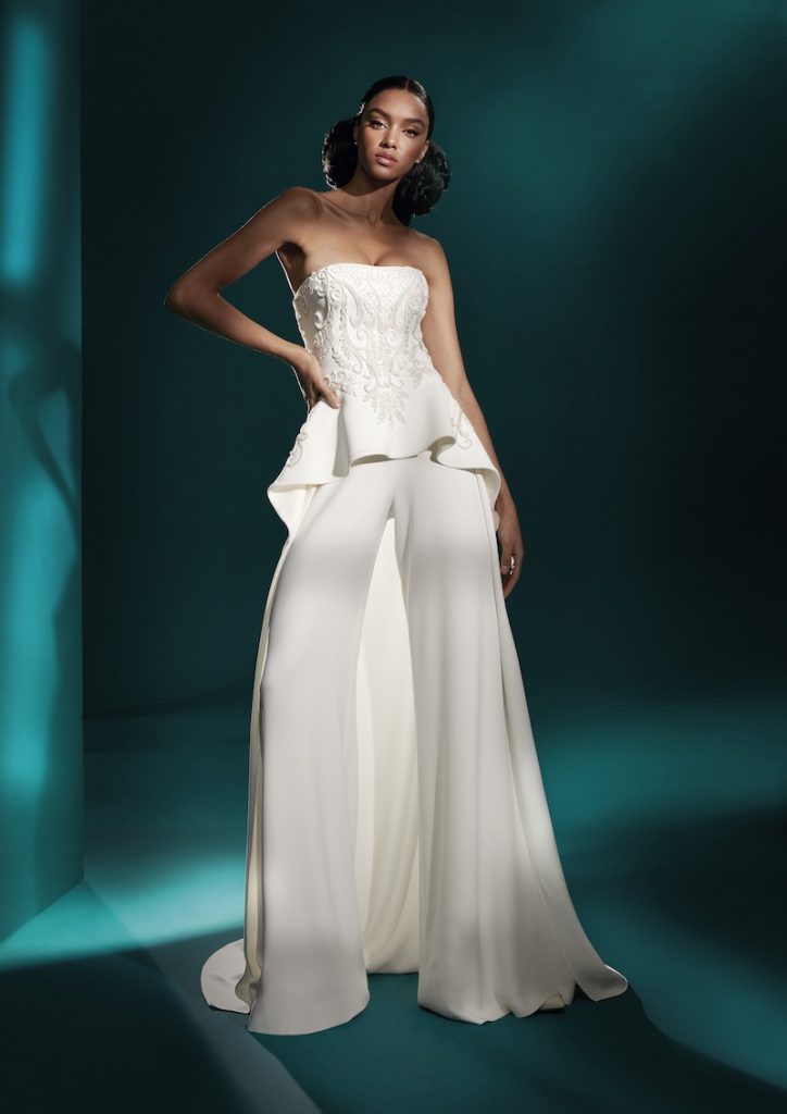 In questa foto una modella indossa un abito da sposa con pantaloni ampi e blusa bustier di Atelier Pronovias