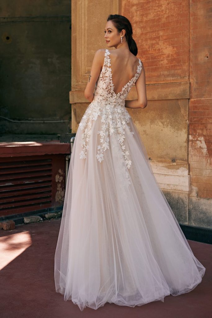 In questa foto una modella indossa un abito da sposa scivolato Annais Bridal in tulle e ricami di fiori 3D sul coperto e sul punto vita