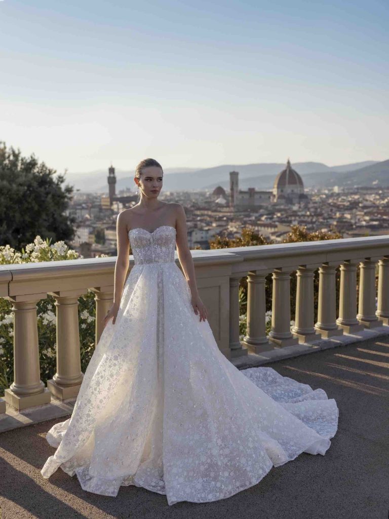 In questa foto una modella indossa un abito da sposa con bustier e gonna scivolata ad A della collezione Ricca Sposa 2023
