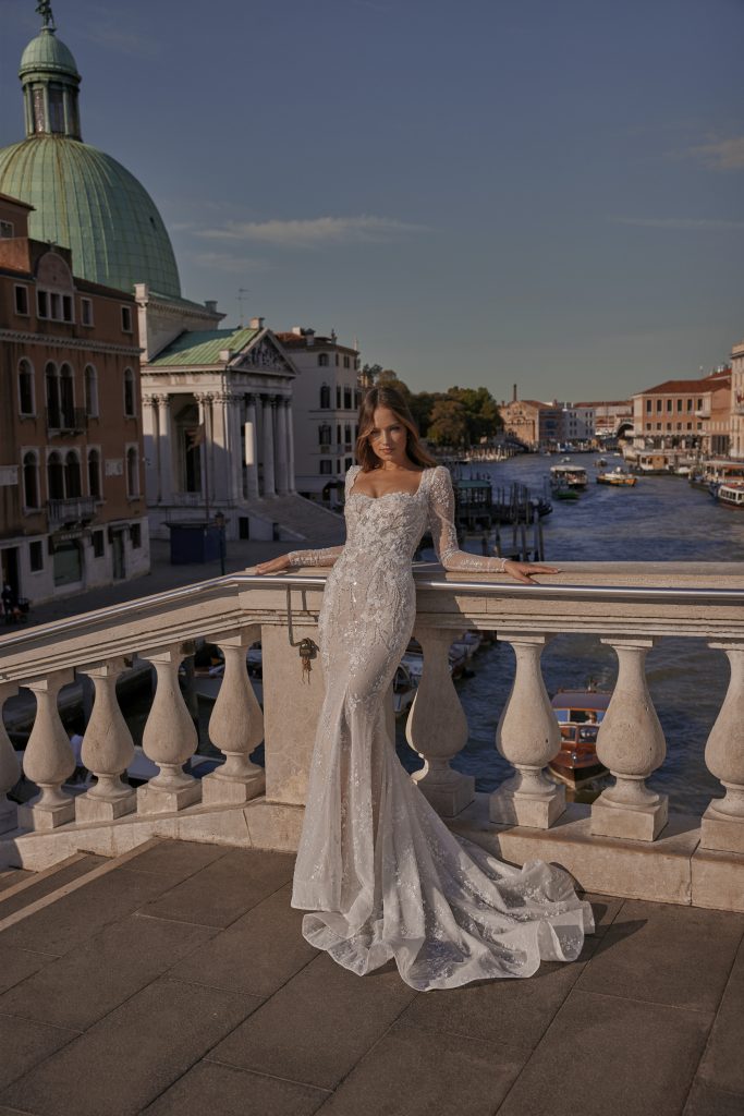 In questa foto una modella posa con un abito da sposa semisirena di Ricca Spose 2023