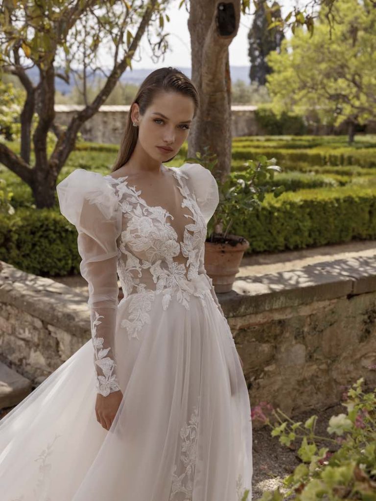 In questa foto una modella mostra le maniche dell'abito della collezione "La mia Italia": sono lunghe, in tulle e a palloncino sulle spalle. I polsi sono incorniciati in ricami floreali