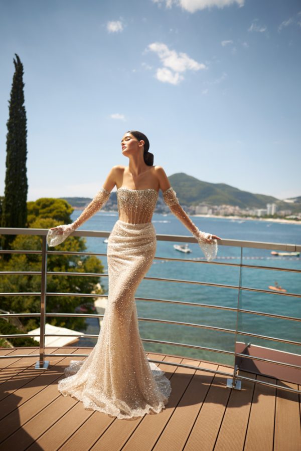 In questa foto una modella indossa un abito da sposa sirena con dettagli gioiello. Le maniche sono removibili