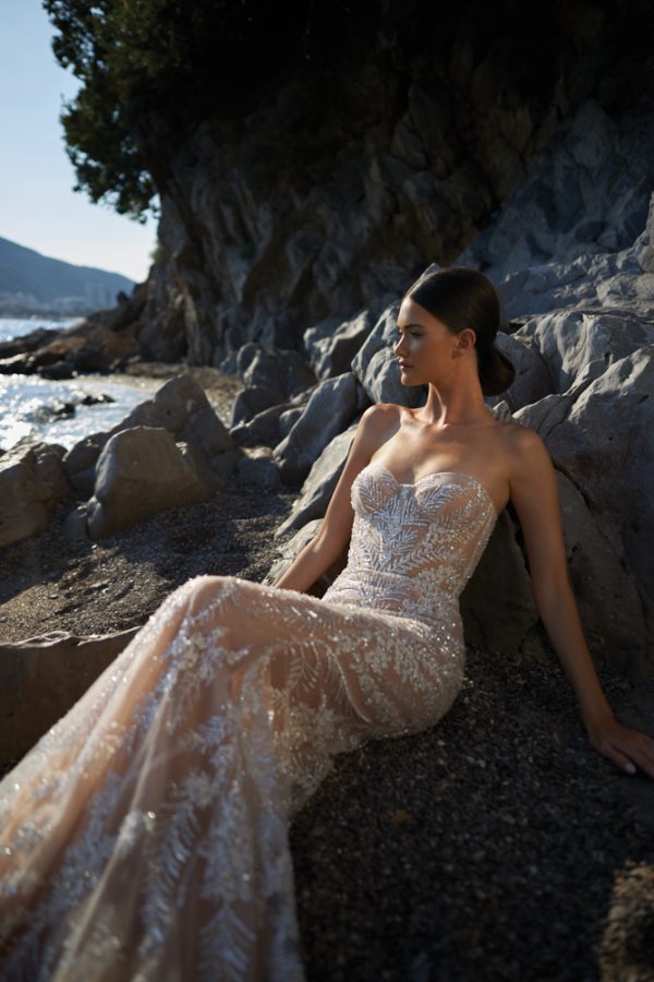 In questa foto una modella indossa un vestito da sposa sirena, con bustier e ricami luminosi all over, della collezione Inbal Dror 2023
