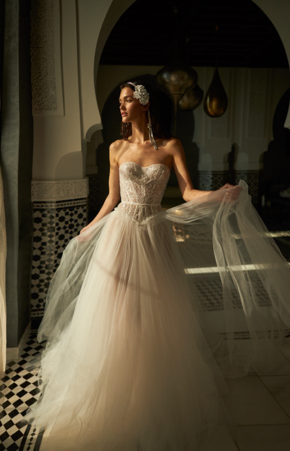 In questa foto una modella indossa un romantico abito da sposa Inbal Dror 2023, con bustier e gonna scivolata e vaporosa in tulle