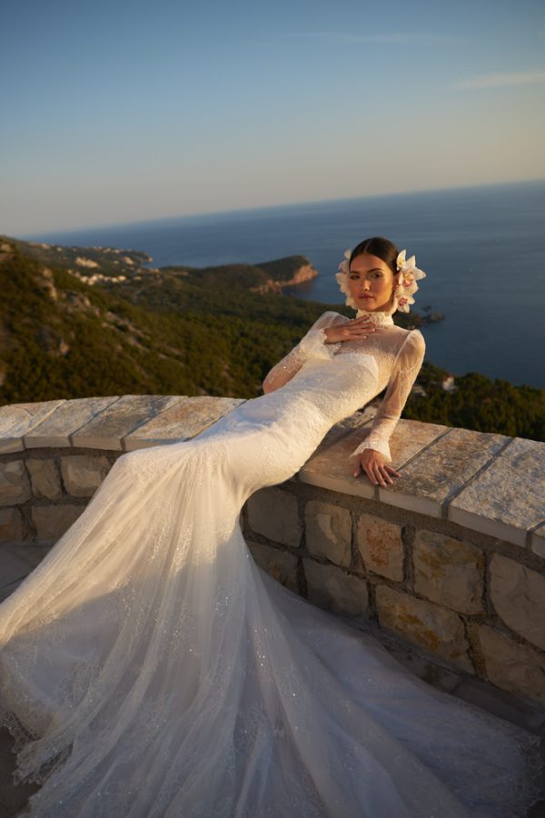In questa foto una modella indossa un abito da sposa sirena, con maniche lunghe e collo alto