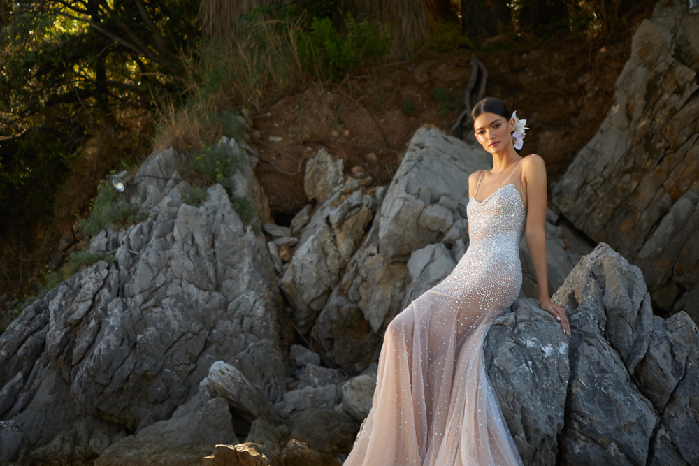 In questa foto una modella indossa un abito da sposa sottoveste, tempestato di perline, della collezione Inbal Dror 2023