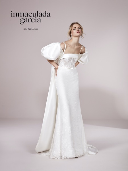 In questa foto una modella indossa un abito da sposa a sirena Inmaculada Garcia 2023. Una giacca over e con maniche a palloncino trasforma il look  