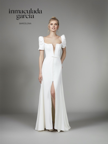 In questa foto una modella indossa un abito da sposa con scollo quadrato e maniche arricciate di Inmaculada Garcia 2023
