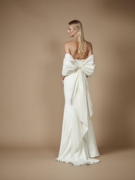In questa foto una modella indossa un abito da sposa 2023 con un fiocco ad incorniciare la schiena