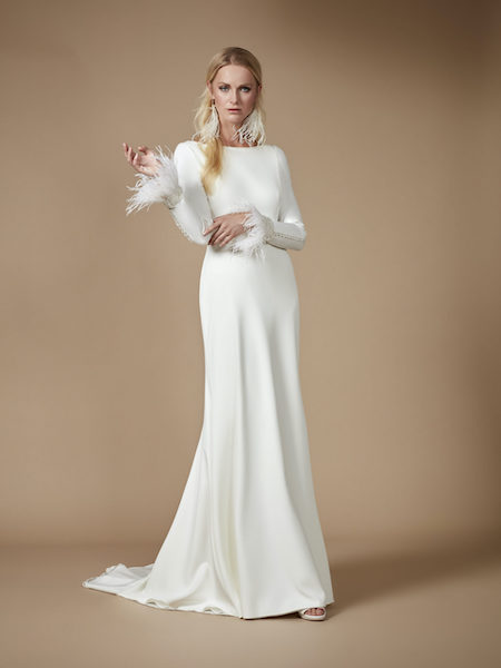 In questa foto una modella indossa un abito da sposa scivolato a sirena, con effetti plumage sui polsini delle maniche