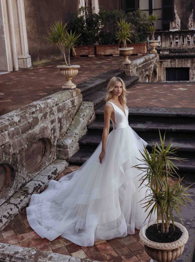 In questa foto una modella un abito da sposa con gonna a balze in tulle di modeca 2023