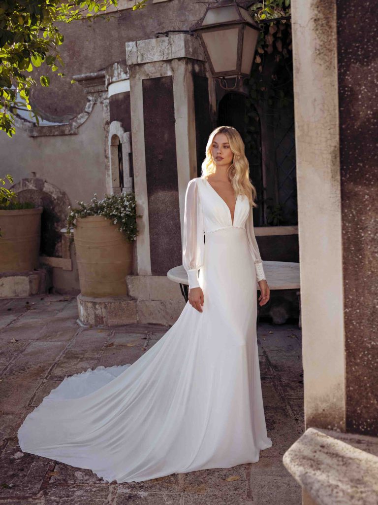 In questa immagine una modella indossa un abito scivolato della collezione sposa di Modeca 2023
