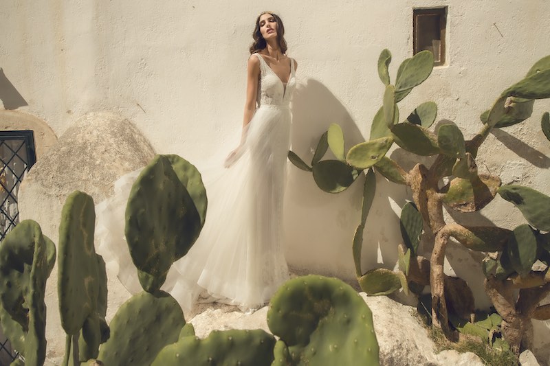 In questa foto una modella indossa un abito da sposa a sirena con sovragonna in tulle removibile