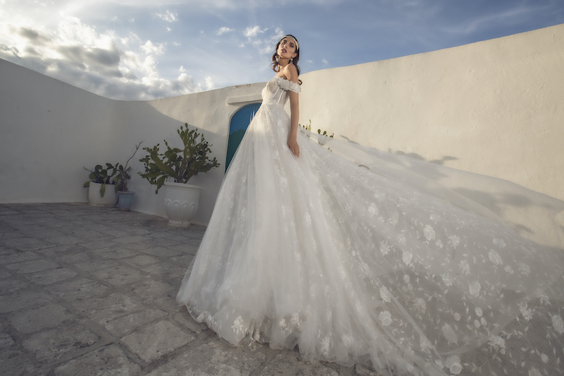 In questa foto una modella indossa un abito da sposa romantico con bustier steccato e gonna scivolata in pizzo chantilly. Il modello è firmato Pietro Demita Haute Couture 2023