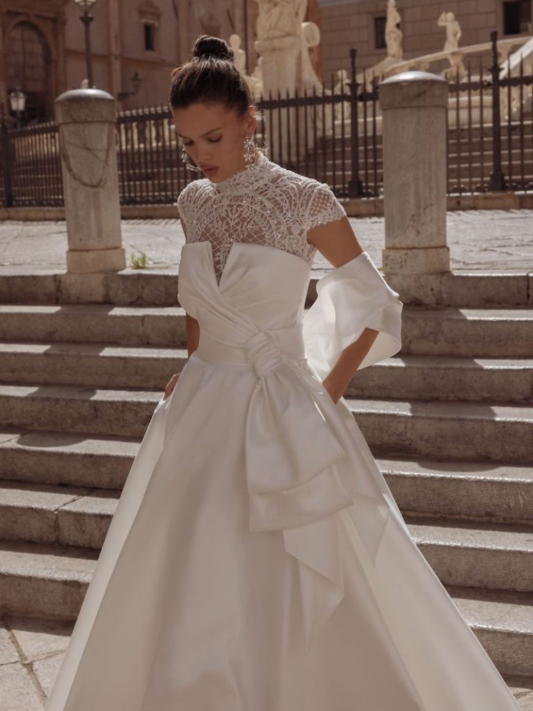 In questa foto una modella indossa un abito da sposa in mikado di seta con inserto in pizzo sul decollete