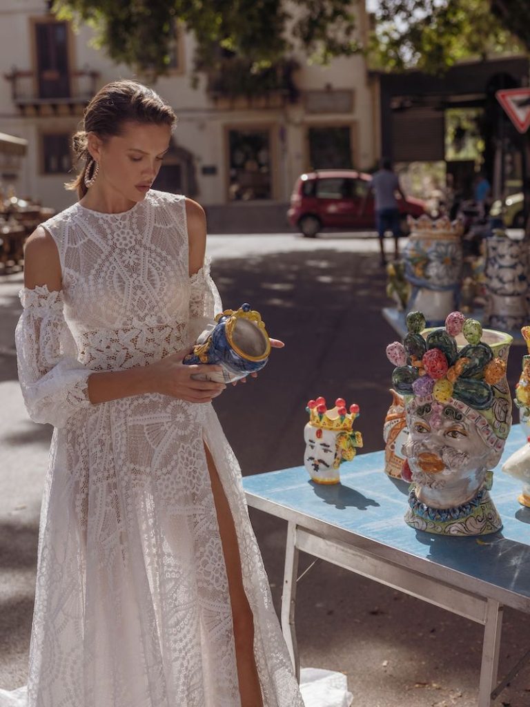 In questa foto una modella guarda una testa di moro indossando uno dei nuovi abiti da sposa Pinella Passaro 2023