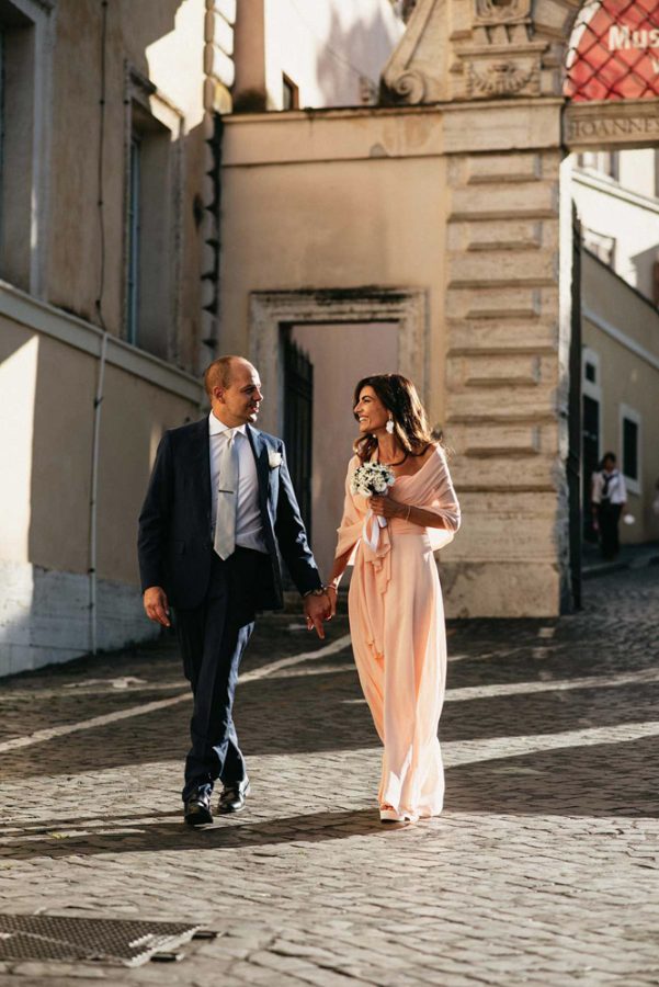 In questa foto realizzata da Fabrizio Musolino, fotografo di matrimonio, una coppia di sposi si tiene per mano in strada