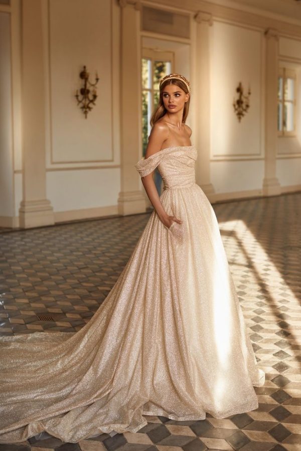 In questa immagine un abito da sposa dal tessuto brillante con cerchietto con maxi pietre.