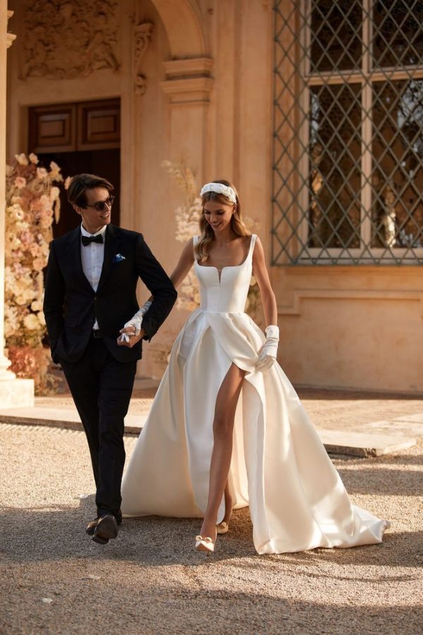 In questa immagine un abito da sposa del brand ucraino con spacco sensuale, guanti e cerchietto bombato.