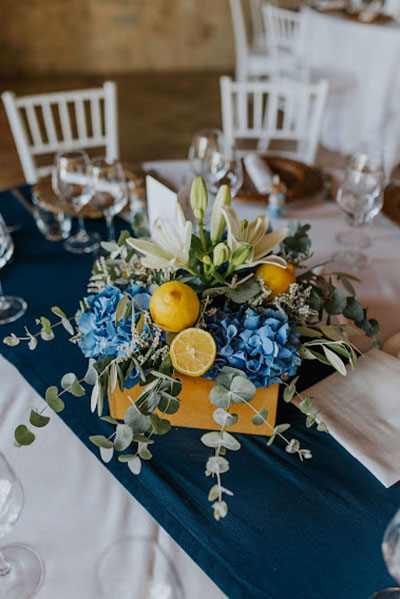 in questa foto un centrotavola floreale realizzato con ortensie azzurro, lilium e limoni