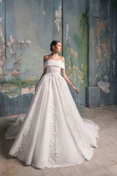 In questa foto una modella indossa un abito da sposa dalla linea ad A con applicazioni floreali sul corpetto e la gonna