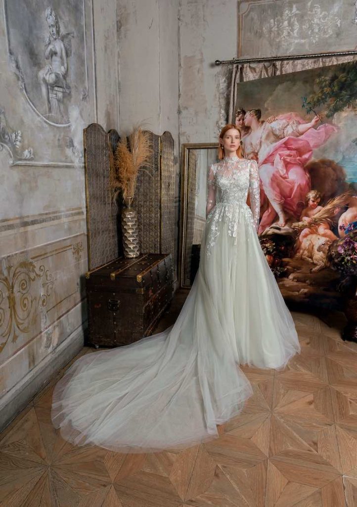 In questa foto una modella indossa un abito da sposa Papilio 2023 in tulle di colore verde salvia, con ramage floreale che dal corpetto a collo alto, maniche lunghe scende sul punto vita