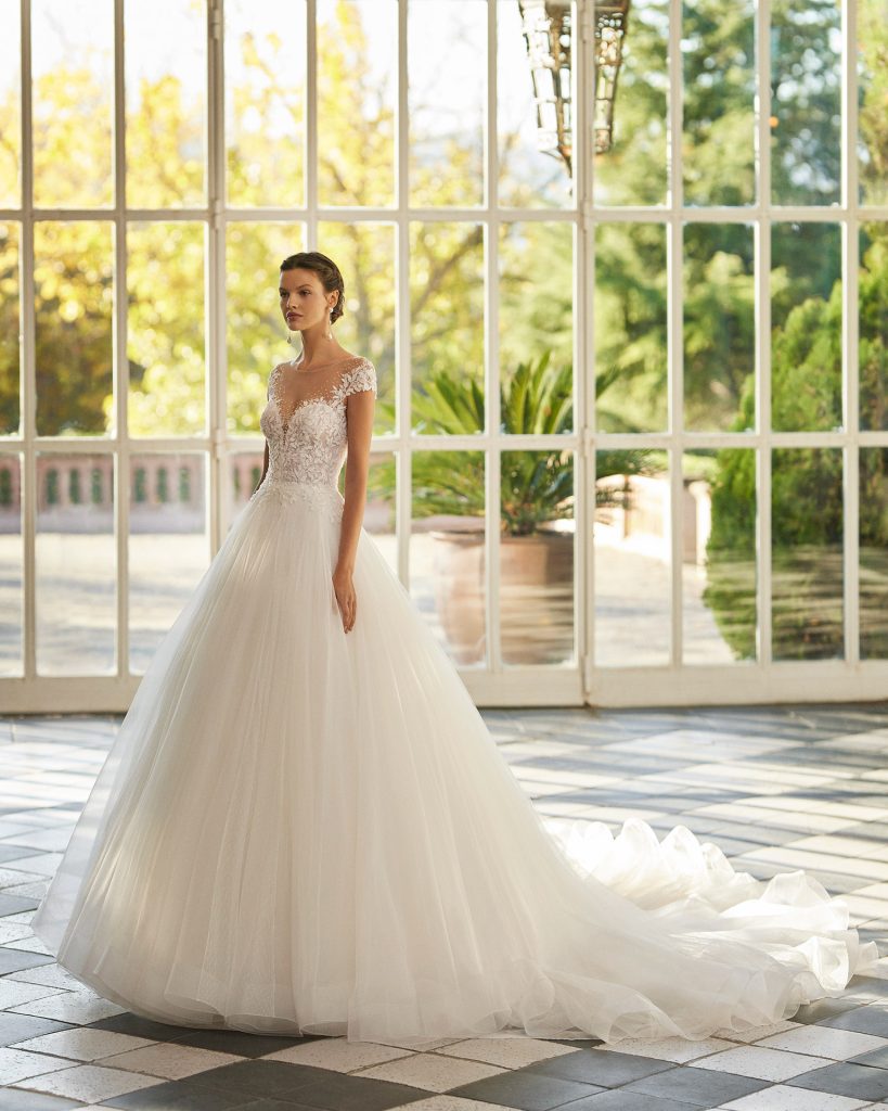 In questa immagine un abito da sposa Aire Barcelona 2023 con corpetto in pizzo e ampia gonna in tulle. 