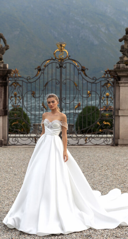 In questa foto una modella, sullo sfondo del Lago di Como, indossa un abito da sposa in mikado di seta off white di Pollardi