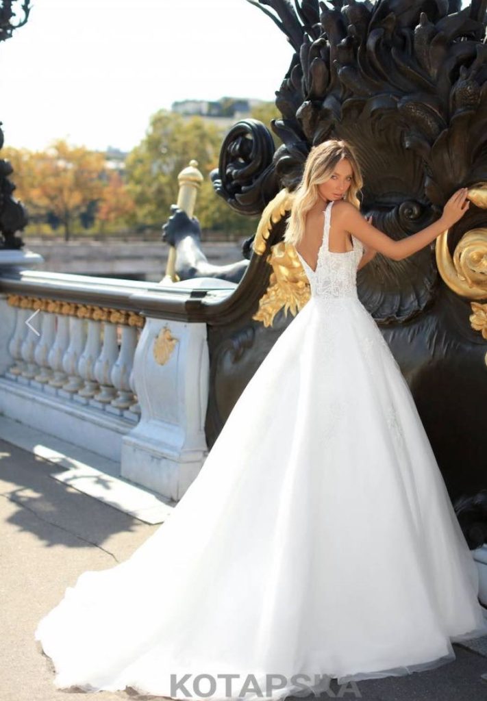 In questa foto una modella ritratta di spalle indossa un abito da sposa ad A con corpetto in pizzo, scollatura ad A sulla schiena, bretelle e gonna in mikado e tulle