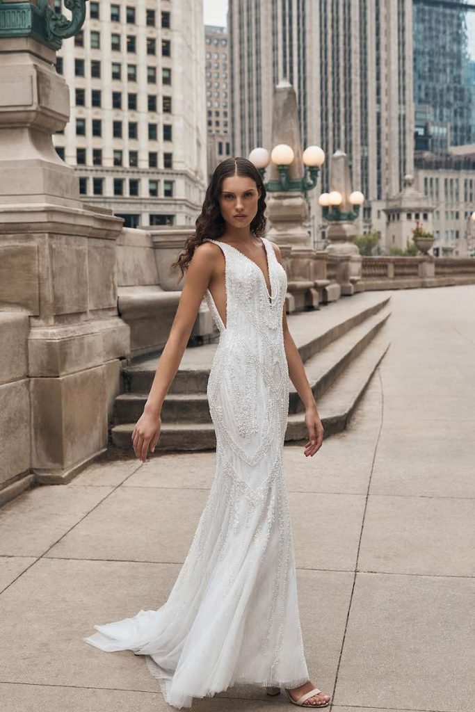 In questa foto una modella indossa un abito da sposa a mezza sirena in tulle di La Premiere Bridal 2023 con scollatura a v e intrecci di perline 