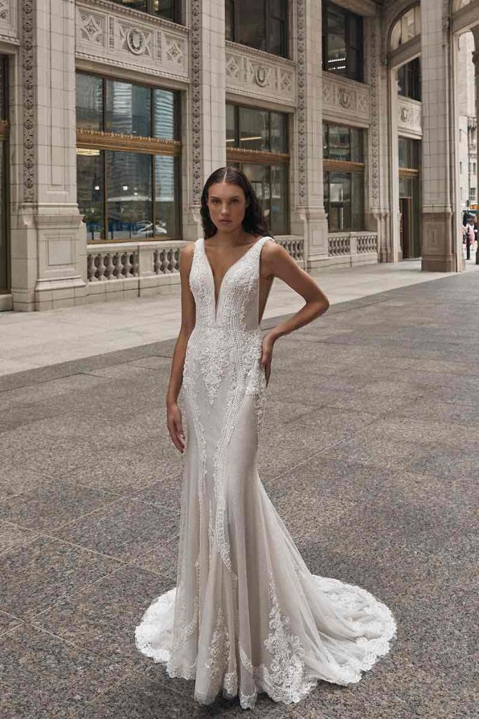 In questa foto una modella indossa un abito da sposa a mezza sirena in tulle di La Premiere Bridal 2023 con scollatura a v, intrecci di perline e pizzo