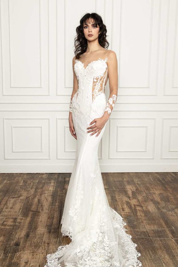 In questa foto una modella indossa un abito da sposa La Premiere Bridal 2023 a sirena in mikado ricoperto in pizzo, scollo a cuore, maniche effetto tattoo sui polsi e dettagli cut-out sui fianchi