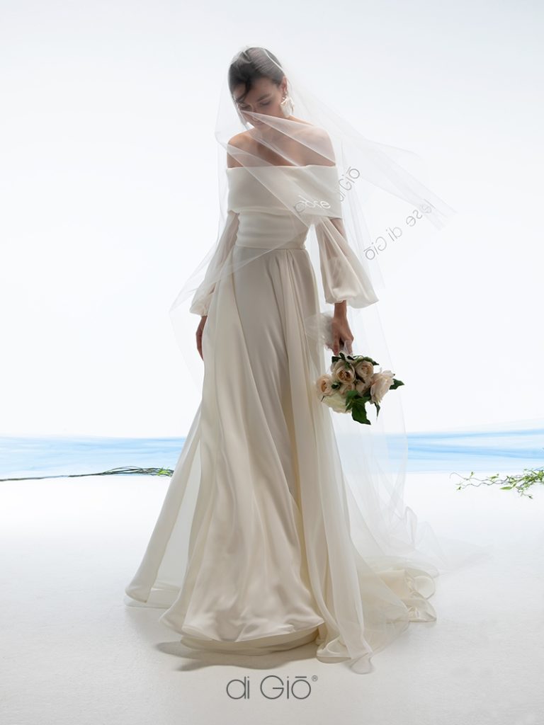 In questa immagine un abito da sposa in seta Le Spose di Giò 2023 con scollo a barca e gonna fluida.