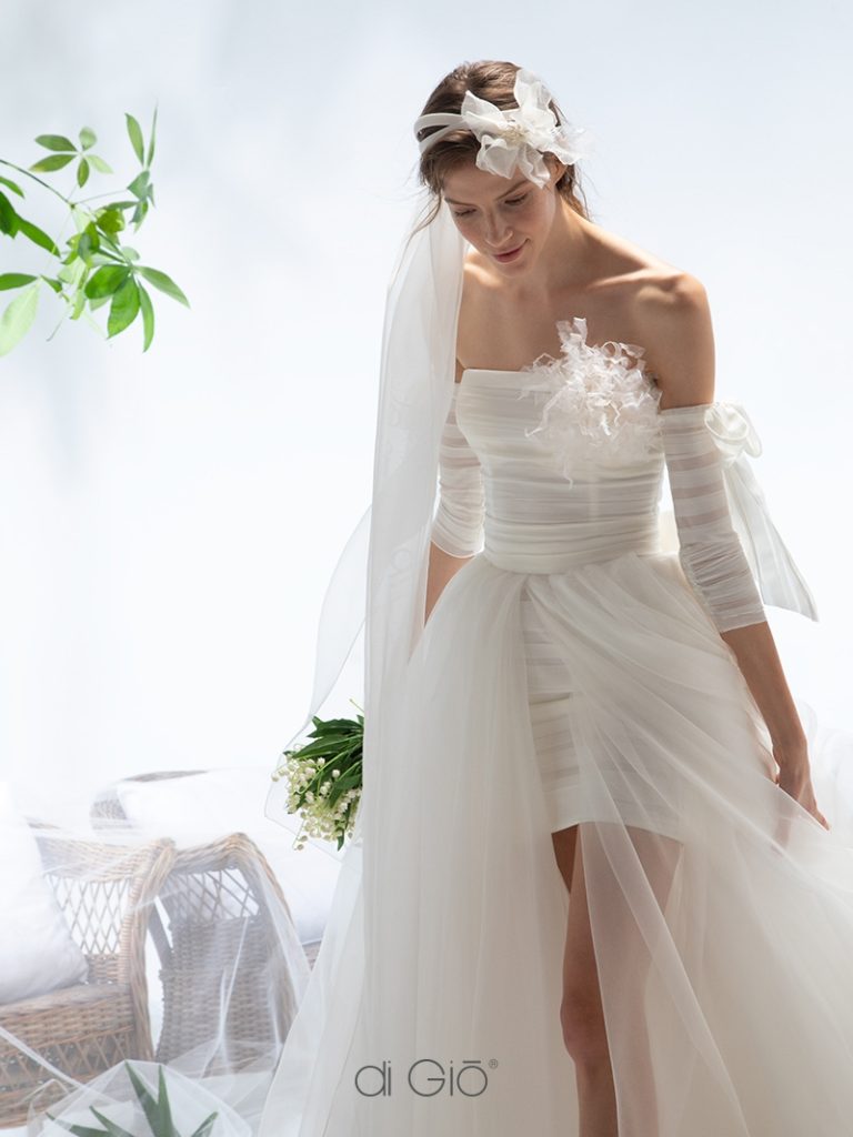 In questa immagine un abito da sposa corto con sopragonna in tulle del brand italiano