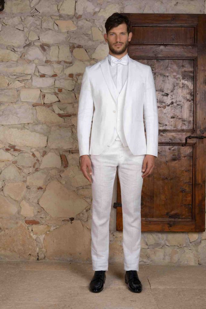 In questa foto il modello indossa un completo in lino bianco. Tutti gli accessori sono nella stessa tonalità. L'outfit fa parte della collezione primavera estate Luigi Convertini 2023