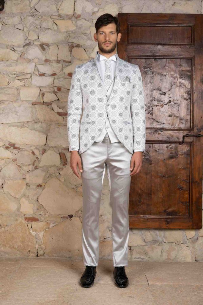In questa foto il modello indossa un abito da sposo total white con motivi damascati in silver. E' una delle proposte più originali della collezione uomo Luigi Convertini 2023