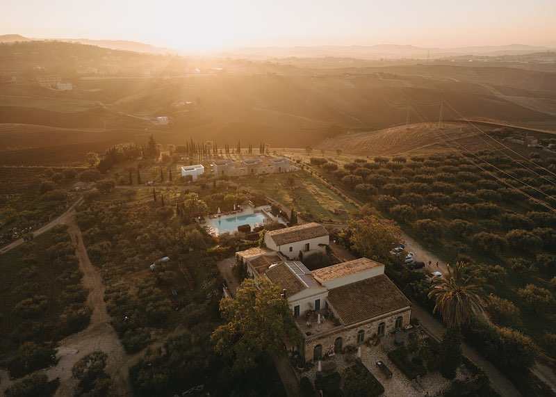 In questa foto la vista dall'alto di un antico casale in Sicilia immerso tra vegetazione e vigneti 