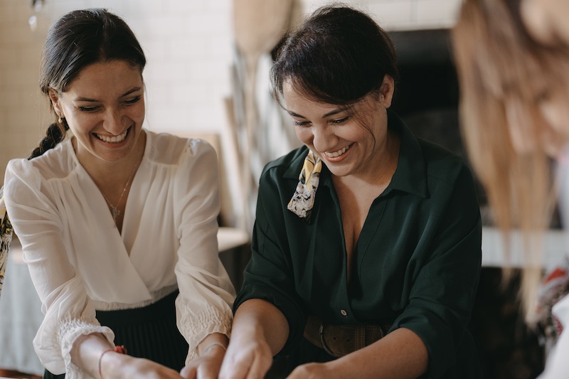 In questa foto la Wedding Planner Tania Costantino ride con una sua collaboratrice mentre impasta in cucina