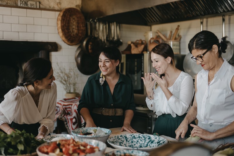 In questa foto la Wedding Planner Tania Costantino ride con le sue collaboratrici in un'antica cucina tra ciotole e piatti 