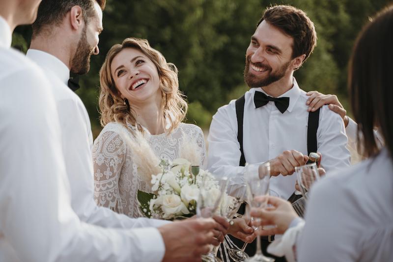 In questa foto due sposi sorridenti circondati 