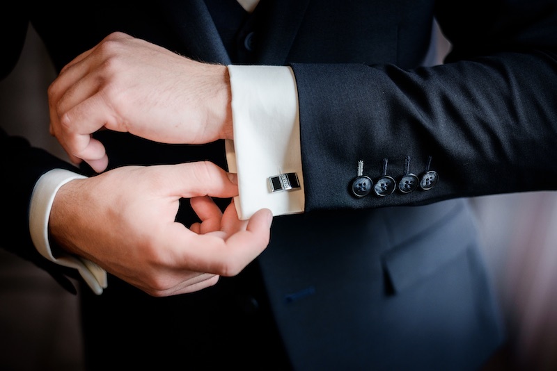 In questa foto il dettaglio di uno sposo che chiude un bottone della camicia per gemelli