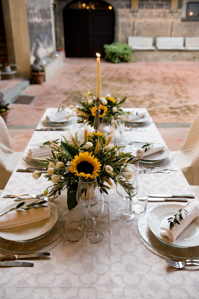 In questa foto la sala esterna di Castello Oliveto allestita per un matrimonio di Wedding by Elisa: la mise en place con girasoli e ulivi