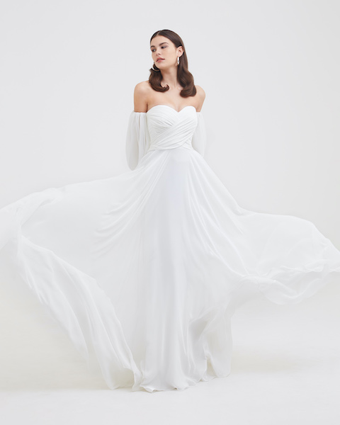 In questa foto una modella indossa un abito da sposa scivolato, con scollatura a cuore e un drappeggio sul top